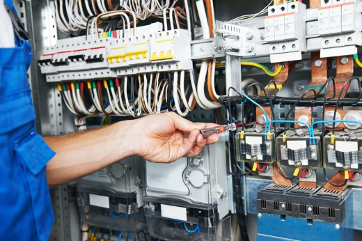 electrician works with electric meter tester in fuse box